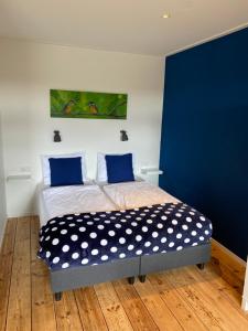 a bedroom with a bed with a blue wall at Studio appartement 1nul9Noord in Renesse