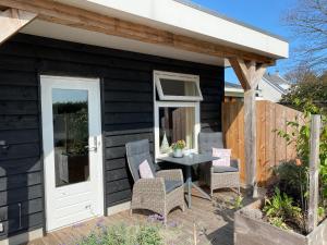 a black house with a patio with a table and chairs at Studio appartement 1nul9Noord in Renesse