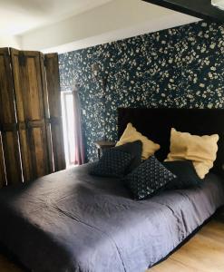 a bedroom with a black bed with a floral accent wall at Les Jardins de la Tuilerie in Jouarre