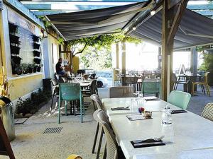 een restaurant met tafels en stoelen en een man op de achtergrond bij HOTEL DU MIDI in Beaufort-sur-Gervanne