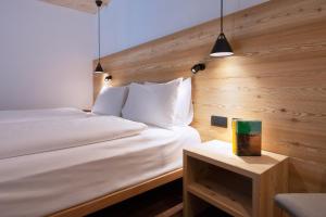 a bedroom with a white bed and a wooden wall at HOTEL B&B MARILENA in Arabba
