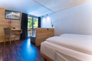 a bedroom with two beds and a desk and a window at HOTEL B&B MARILENA in Arabba