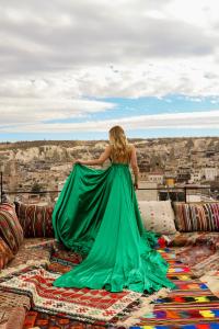 a woman in a green dress standing on a pile of carpet at Nessa Cave Hotel in Goreme