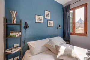 um quarto com paredes azuis e uma cama com almofadas brancas em Mamo Florence - San Marco Apartment em Florença