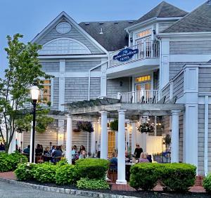 a large white building with people sitting in front of it at Inn on Main Hotel in Manasquan