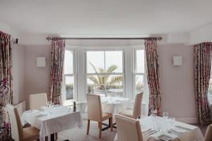 a dining room with white tables and chairs and a window at The Bay Hotel in Coverack