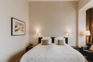 - une chambre avec un grand lit blanc et une chaise dans l'établissement Grand Hotel Belle Vue, au Coq