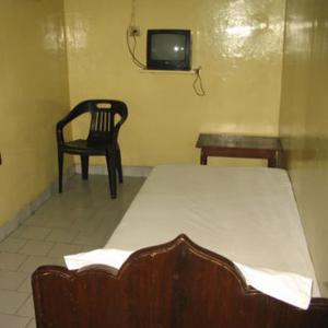 een kamer met een bed, een stoel en een tv bij Vasantha Lodge Purasawalkam chennai in Chennai