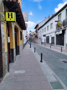 an empty street in a town with a yellow building at H Los Rafaeles in Torrejón de Ardoz