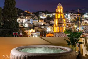 a bath tub with a view of a city at night at Maravelia's Rooms in Symi