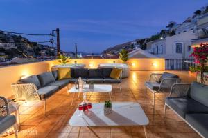 a patio with couches and tables on a roof at Maravelia's Rooms in Symi