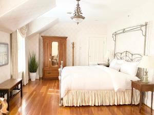 a bedroom with a white bed and a wooden floor at Princess and the Pea Hotel in Langley