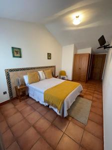 1 dormitorio con 1 cama grande con manta amarilla en Pensión Biazteri, en Laguardia