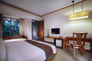 Schlafzimmer mit einem Bett, einem Schreibtisch und einem TV in der Unterkunft ASTON Sunset Beach Resort - Gili Trawangan in Gili Trawangan