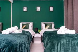 zwei Betten in einem Zimmer mit grünen Wänden in der Unterkunft Cheerful 2 Bedroom Homely Apartment, Sleeps 4 Guest Comfy, 1x Double Bed, 2x Single Beds, Free Parking, Free WiFi, Suitable For Business, Leisure Guest, Contractors, QE Hospital, Glasgow, Near Airport & City Centre in Glasgow