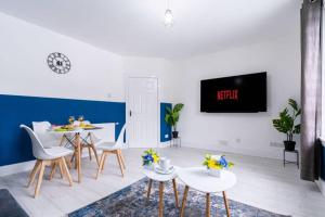 ein Wohnzimmer mit Tisch und Stühlen und einem Fernseher in der Unterkunft Cheerful 2 Bedroom Homely Apartment, Sleeps 4 Guest Comfy, 1x Double Bed, 2x Single Beds, Free Parking, Free WiFi, Suitable For Business, Leisure Guest, Contractors, QE Hospital, Glasgow, Near Airport & City Centre in Glasgow