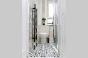 ein Bad mit einem WC und einem schwarz-weißen Fliesenboden in der Unterkunft Cheerful 2 Bedroom Homely Apartment, Sleeps 4 Guest Comfy, 1x Double Bed, 2x Single Beds, Free Parking, Free WiFi, Suitable For Business, Leisure Guest, Contractors, QE Hospital, Glasgow, Near Airport & City Centre in Glasgow