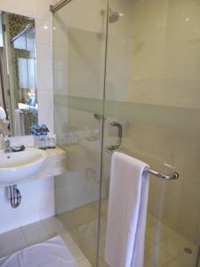 a bathroom with a glass shower and a sink at Neo Hotel Melawai by ASTON in Jakarta