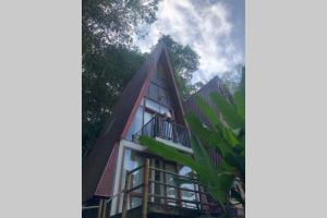 a house with a pointed roof and a tree at LANDE Tiny in Rantepao