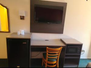 Habitación con escritorio y TV en la pared. en Windsor Inn Lake Havasu City, en Lake Havasu City