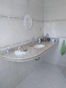 un bancone del bagno con lavandino e specchio di Cantinho da paz 01 a Caraguatatuba