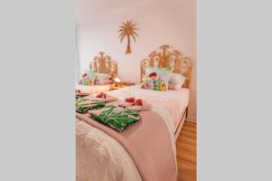 2 camas en una habitación con sábanas rosas y verdes en The Coconut Crib- Waterfront Burleigh Beach, en Gold Coast