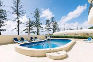 a swimming pool with lounge chairs and a pool at The Coconut Crib- Waterfront Burleigh Beach in Gold Coast