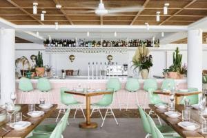 a restaurant with green chairs and tables and a bar at The Coconut Crib- Waterfront Burleigh Beach in Gold Coast