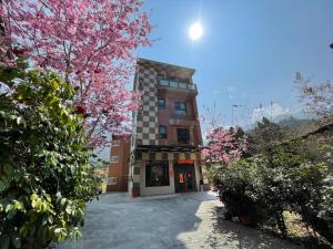 a building with pink flowering trees in front of it at Sin Ging Hong Resort in Lugu Lake