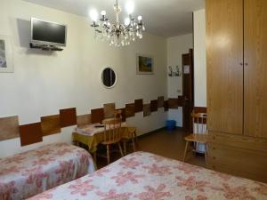 Habitación con 2 camas, mesa y lámpara de araña. en Hotel Beau Séjour, en Aosta