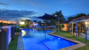 a swimming pool in front of a house at night at Yamba Motor Inn in Yamba