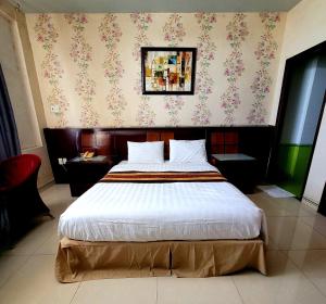 Hồ Tây Hotel في Thu Dau Mot: غرفة نوم مع سرير كبير مع زهور على الحائط