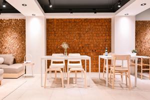 a dining room with white tables and chairs and a brick wall at Hommie Inn in Taichung