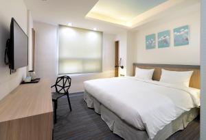 a bedroom with a large white bed and a flat screen tv at Hommie Inn in Taichung