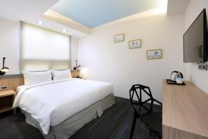ein Schlafzimmer mit einem großen weißen Bett und einem Flachbildfernseher in der Unterkunft Hommie Inn in Taichung