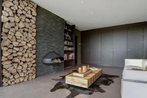a living room with a fireplace and a pile of logs at B&B Finis terrae in Lokeren