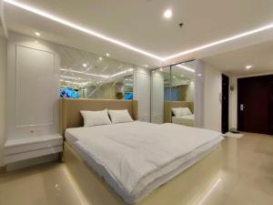 ein Schlafzimmer mit einem großen weißen Bett und einem Spiegel in der Unterkunft Platinum 1010 Studio Tera Apartemen Bandung City View in Bandung
