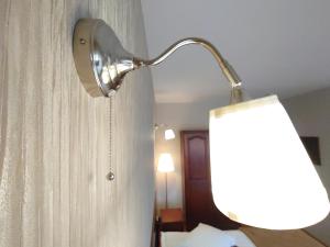 a lamp hanging on a wall next to a curtain at Pensiunea Mușatinii in Putna