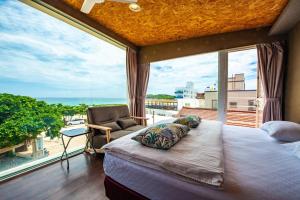 a bedroom with a large window with a bed and a chair at Mahalo B&B in Magong