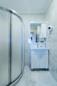 イスタンブールにあるAtam Suitesのガラスのシャワーと洗面台を備えたバスルーム