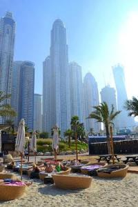 a group of people laying on a beach in front of a city at SKY NEST HOMES PRIVATE 1 BEDROOM APARTMENT DUBAI MARINA in Dubai