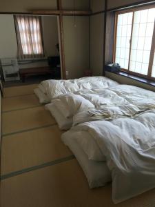 a large bed with white sheets on the floor at Aigakusou in Nozawa Onsen