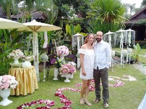 
a man and woman standing next to each other in front of flowers at Homestay Chiangrai in Chiang Rai
