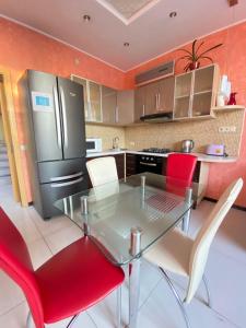 eine Küche mit einem Glastisch und roten Stühlen in der Unterkunft Таунхаус 99 in Petropavlovskaya Borshchagovka