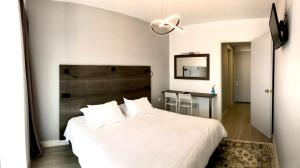 サモスにあるHotel Anthousaの白いベッド1台(木製ヘッドボード付)が備わるベッドルーム1室が備わります。