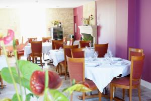 a restaurant with white tables and chairs and purple walls at Logis- Hôtel Spa Restaurant l'Epicurial in Saint-Pey-de-Castets
