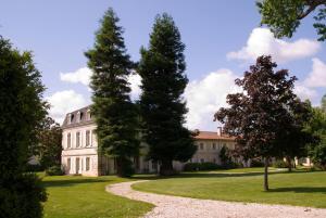 ein großes weißes Haus mit Bäumen im Vordergrund in der Unterkunft Relais de Margaux - Hôtel & Spa in Margaux