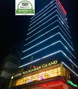a tall building with a neon sign on the side of it at Hotel Noorjahan Grand in Sylhet