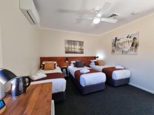 um quarto de hotel com três camas e uma secretária em Black Sheep Motel Goulburn em Goulburn