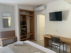 a bedroom with a bed and a desk and a television at Miriasol Bed and Breakfast in Capo Vaticano